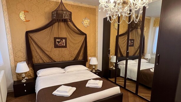 Une chambre d’hôtel avec un grand lit, un lustre, un miroir et une table de chevet avec une lampe.