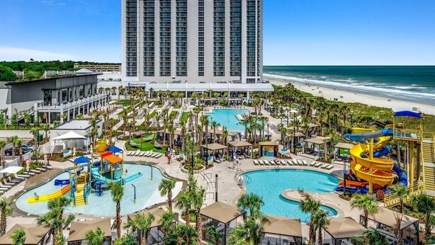 A resort with multiple swimming pools, a beach, and a tall hotel building. - Ocean Front Crown New Remodel (MYRTLE BEACH)