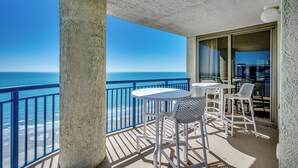 A balcony with a view of the ocean, white outdoor furniture, and a concrete pillar. - Ocean Front Crown New Remodel (MYRTLE BEACH)