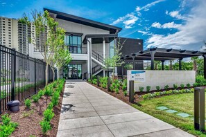 A modern building with a covered walkway, a sign for Black Drum, and a landscaped garden area. - Ocean Front Slice of Heaven (MYRTLE BEACH)