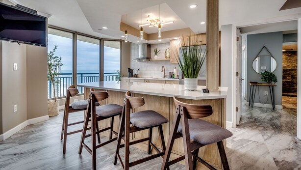 Cozinha moderna com uma ilha grande, banquetas e vista para o exterior.
