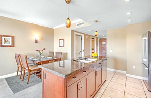 A modern kitchen with a granite countertop, stainless steel appliances, and pendant lighting.