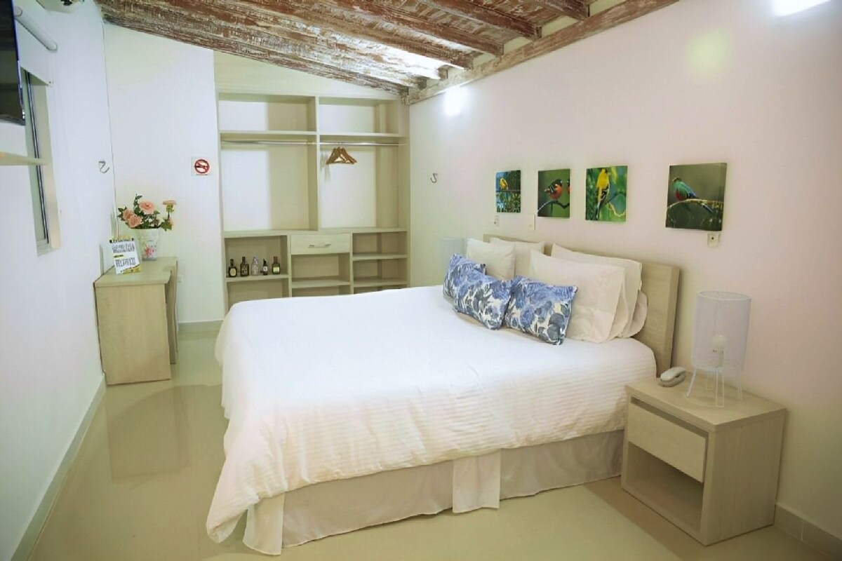 A bedroom with a bed, bedside tables, a wardrobe, and wall art.