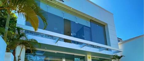 Un edificio moderno con techo plano, ventanas amplias y césped cuidado.