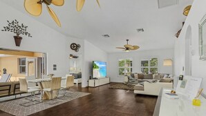 A spacious living area with a dining set, a sofa, and a TV. - Villa Tuscany: Luxury Stay with Pool & Spa (Cape Coral)