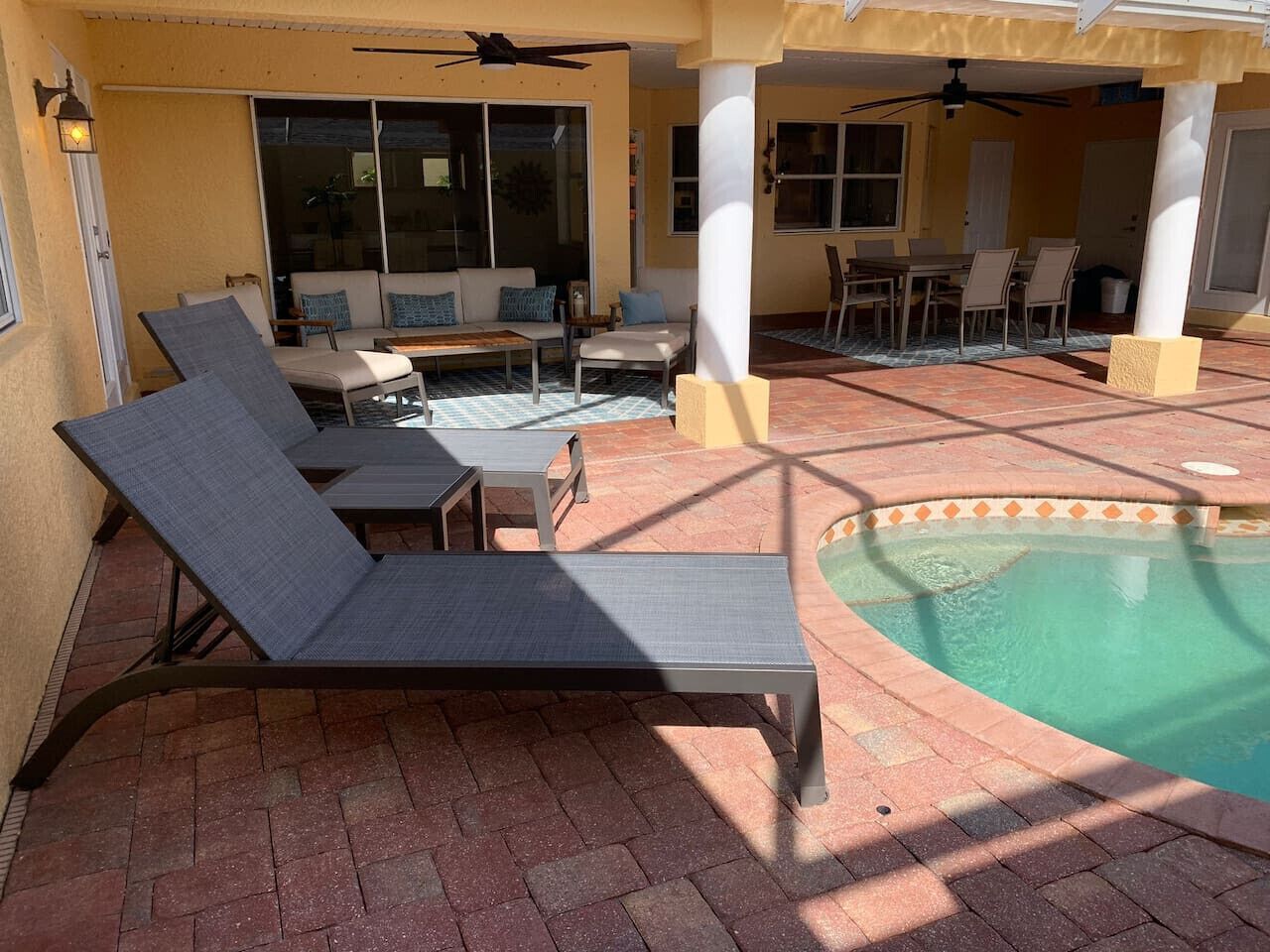 Un área junto a la piscina con sillones, una mesa y una pileta.