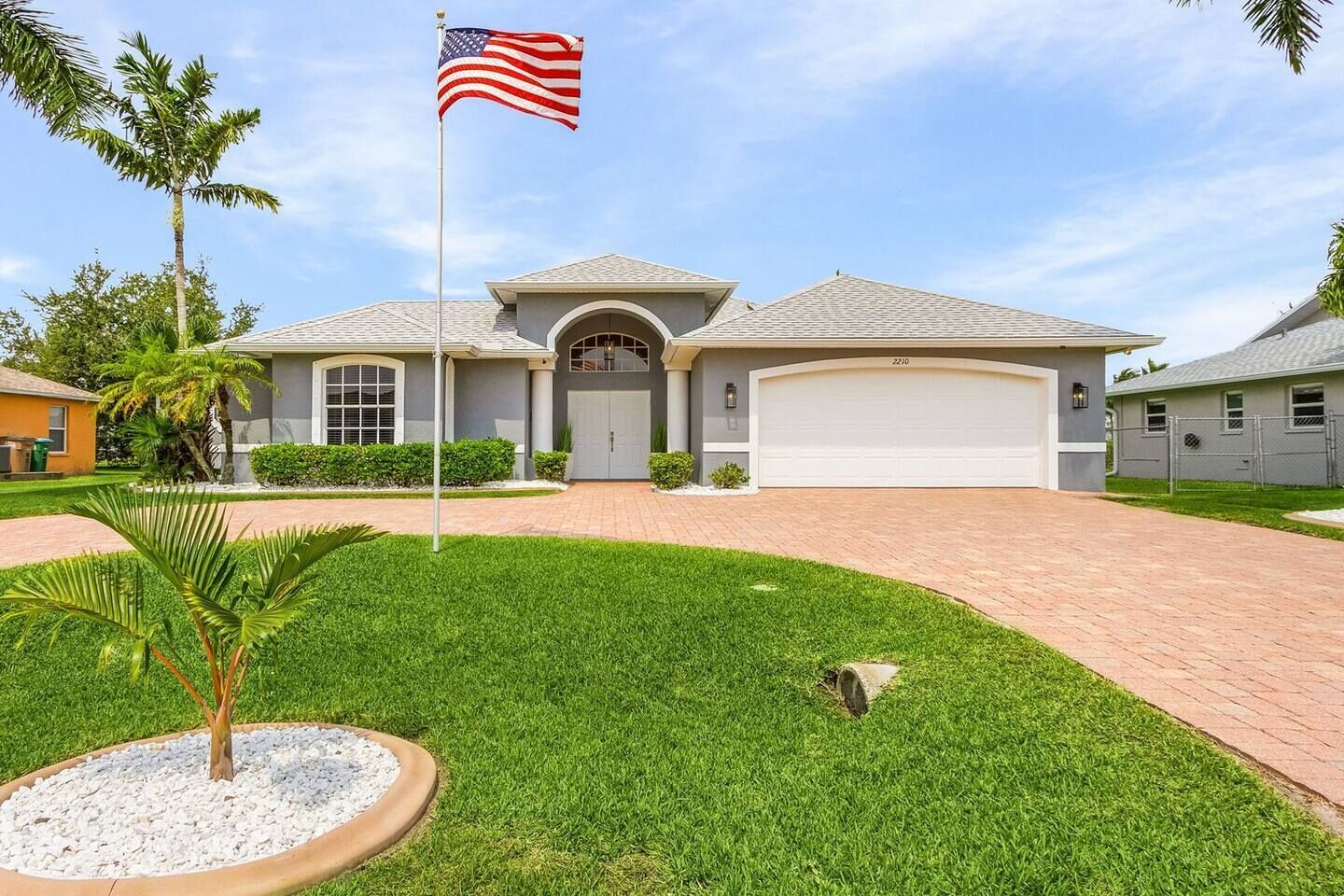 Een twee verdiepingen tellend huis met garage, een verzorgd gazon en een vlaggenmast met de Amerikaanse vlag.