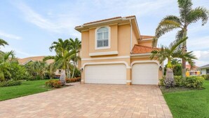 A two-story house with a tiled roof, a garage, and a paved driveway. - Villa American Beauty (Cape Coral)