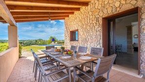 Eine Terrasse im Freien mit einer Steinmauer, einem Holztisch und Stühlen.