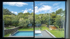Habitación moderna con un amplio ventanal corredero que da a un espacio exterior privado con piscina y jacuzzi.