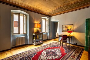 Classic design with ornate ceiling, hardwood floor, and patterned rug. Offers a table, chair, and radiator for comfort.