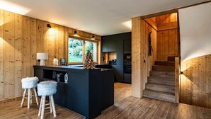 Une cuisine moderne avec des murs en bois, un îlot central doté de tabourets et un escalier menant à un niveau supérieur.