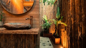 A bathroom with a wooden vanity, a round mirror, and a stone basin. - Selva Ecospa Wellness Stay (Guatapé)