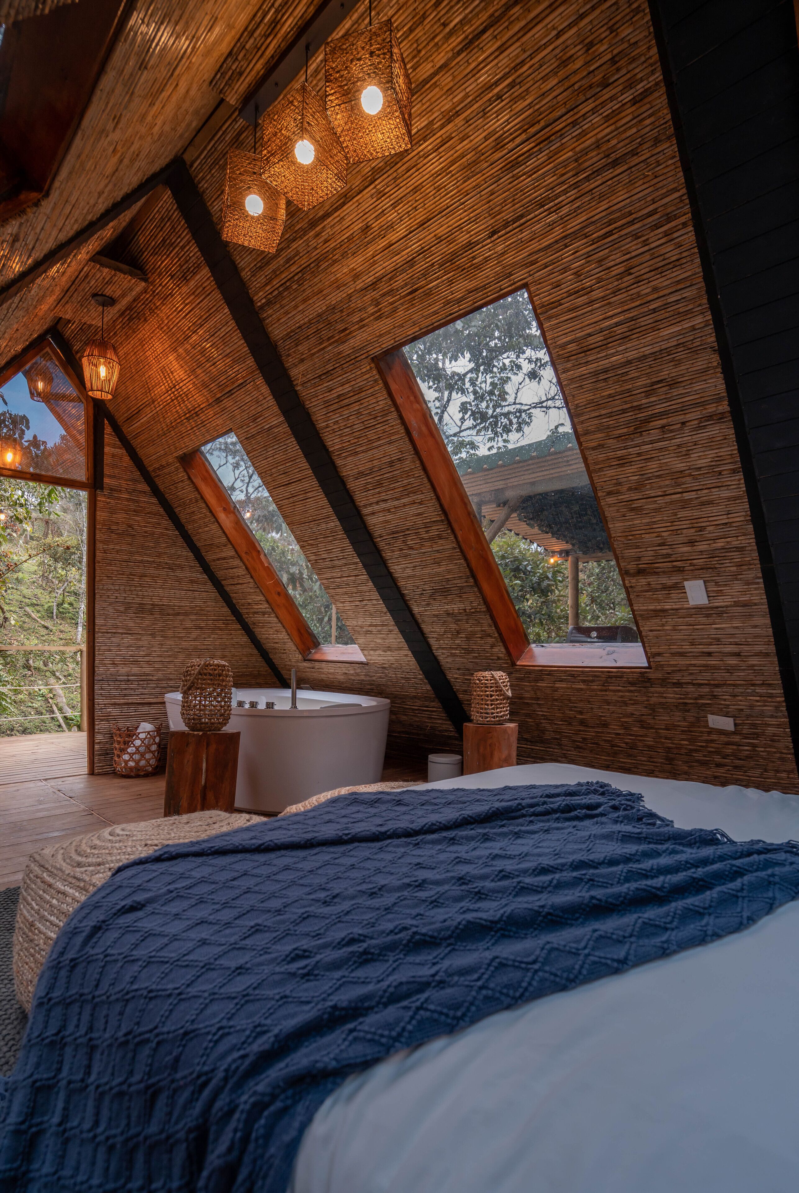 Un dormitorio con una cama grande, una bañera y vistas a árboles por una ventana.