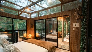 A spacious bedroom with a large bed, a glass door leading to a balcony, and a wooden ceiling. - Selva Ecospa Wellness Stay (Guatapé)