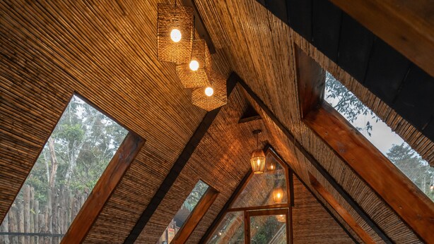 A cozy attic bedroom with a large bed, a hanging chair, a bathtub, and a view of the outdoors through a large window. - Selva Ecospa Wellness Stay (Guatapé)