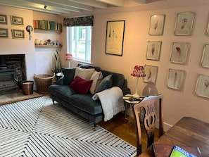 A cozy living room with a fireplace, a sofa, a dining table, and various framed pictures on the walls.
