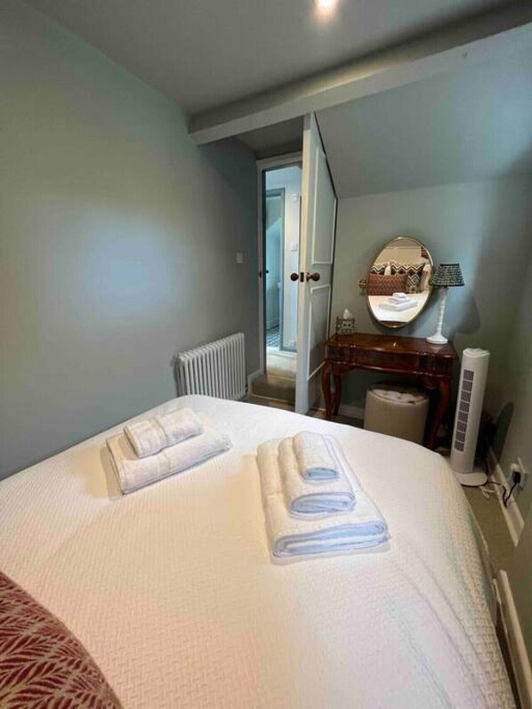 A hotel room with a bed, a bedside table with a lamp, a mirror, and a radiator.