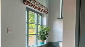 A staircase with beige carpeted steps leading to a landing with a window. - Luxury Cottage with Garden (Tewkesbury)