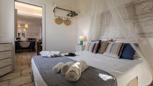 A bedroom with a bed, a bedside table, a lamp, and a window with a sheer curtain. - Villa Alexandra - Villa with pool (Ispica)