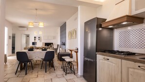 A modern kitchen with a large refrigerator, a dining area with a table and chairs, and a kitchen island with stools. - Villa Alexandra - Villa with pool (Ispica)