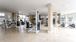 Ein geräumiges Fitnessstudio mit verschiedenen Trainingsgeräten, großen Fenstern und einem modernen, aufgeräumten Design.