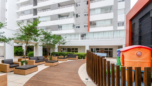 Ein moderner Außenbereich mit Holzterrasse, Korbmöbeln und einer Spielanlage für Kinder.