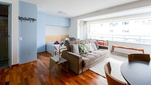 Ein modernes Wohnzimmer mit einer Couch, einem Esstisch und einem großen Fenster mit Blick auf die Stadt.