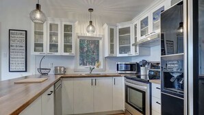 A modern kitchen with white cabinetry, stainless steel appliances, and pendant lighting.