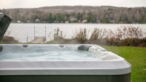 A hot tub with a view of a lake and hills in the background.