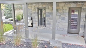 Un bâtiment moderne avec une façade en pierre, un patio couvert et une porte donnant sur un garage.