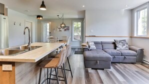 Une cuisine moderne dotée d’un îlot central, de tabourets de bar et de luminaires suspendus.