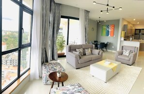 Relax in this stylish living room with a city view, featuring a sofa set, armchairs, and a dining area.