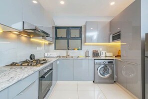 Enjoy cooking in this well-lit kitchen with oven, microwave, and stainless steel washing machine.