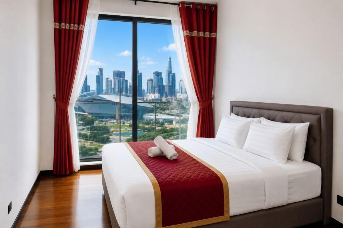 A hotel room with a large bed, red curtains, and a cityscape view.