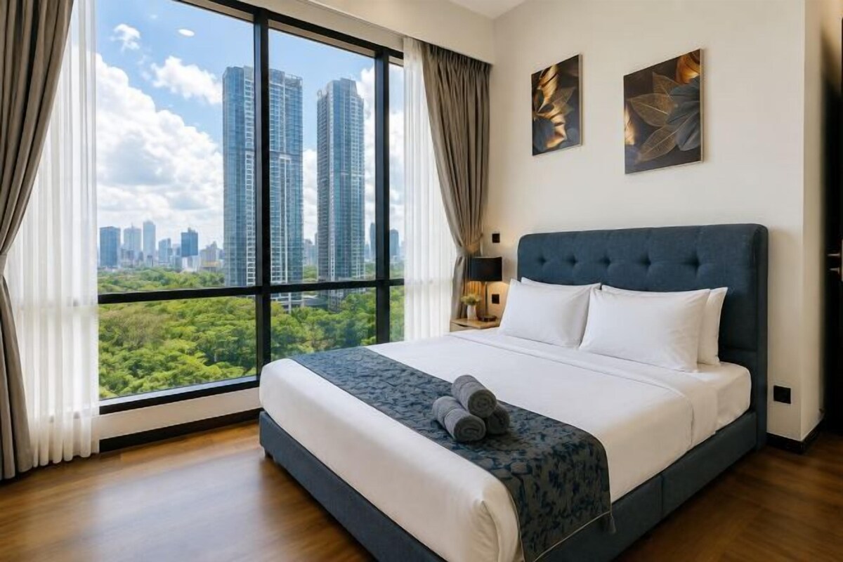 A hotel room with a large bed, a view of the cityscape, and a city skyline visible through the window.