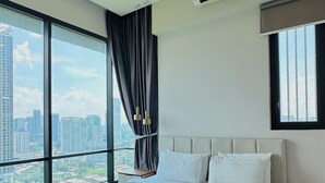A modern hotel room with a large bed, a ceiling fan, an air conditioning unit, a city view, and a large window with curtains. - Opus Residences Merdeka Tower KL (Kuala Lumpur)