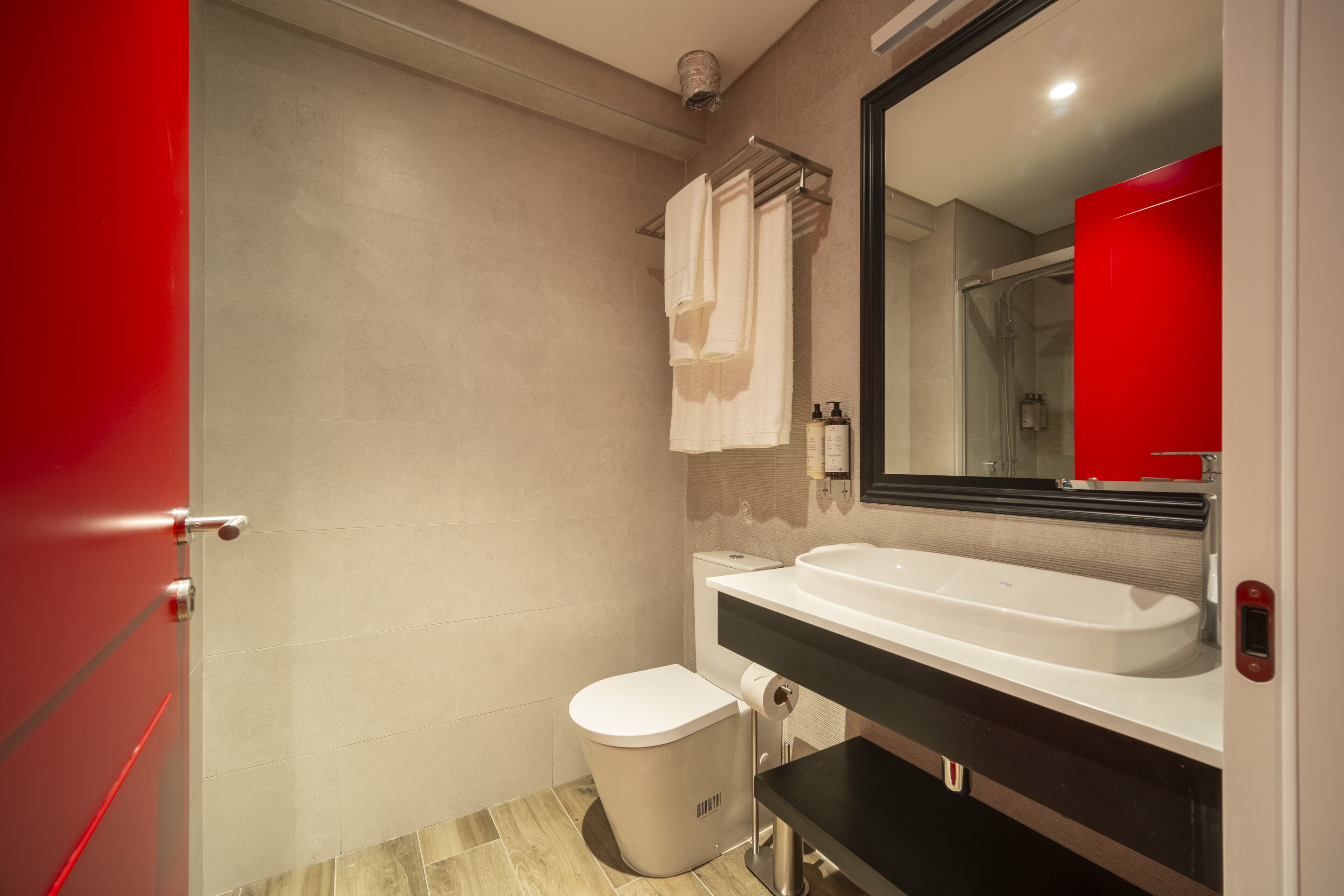 A modern bathroom with a white sink, a toilet, and a shower.