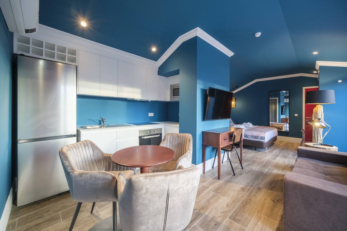 Een knus woongedeelte met kitchenette, een eethoek met twee stoelen, een bank, een televisie en een bed.
