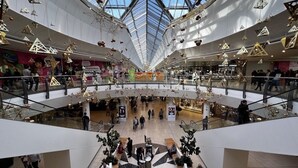 Un centro comercial de varios niveles con un atrio central, escaleras mecánicas y una amplia variedad de tiendas.