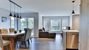 Une cuisine moderne avec une table à manger en bois, des chaises et des luminaires suspendus.