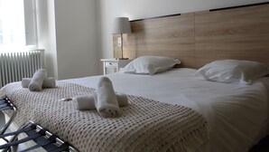 A hotel room with a large bed, two pillows, a bedside table with a lamp, and a window with blinds. - Le Grand Couvent de Gramat (Gramat)