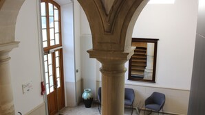 A hallway with a wooden door, a radiator, and a vase. - Le Grand Couvent de Gramat (Gramat)