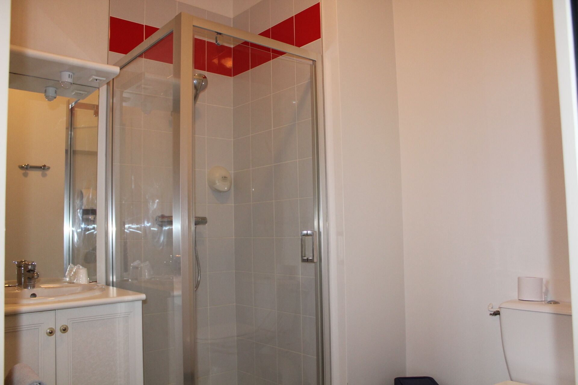 Un baño con ducha envuelta en vidrio, lavamanos e inodoro.
