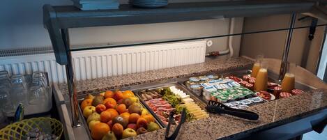 Un bufé con diversas opciones de comida, como frutas, quesos y bebidas.