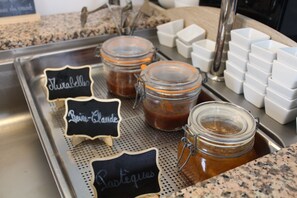 Una encimera de cocina con tres tarros de vidrio etiquetados como 'Thé', 'Raisin-Clande' y 'Lactées'.