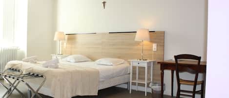 Habitación de hotel con cama, lámparas de noche, cabecera de madera, escritorio y una silla.