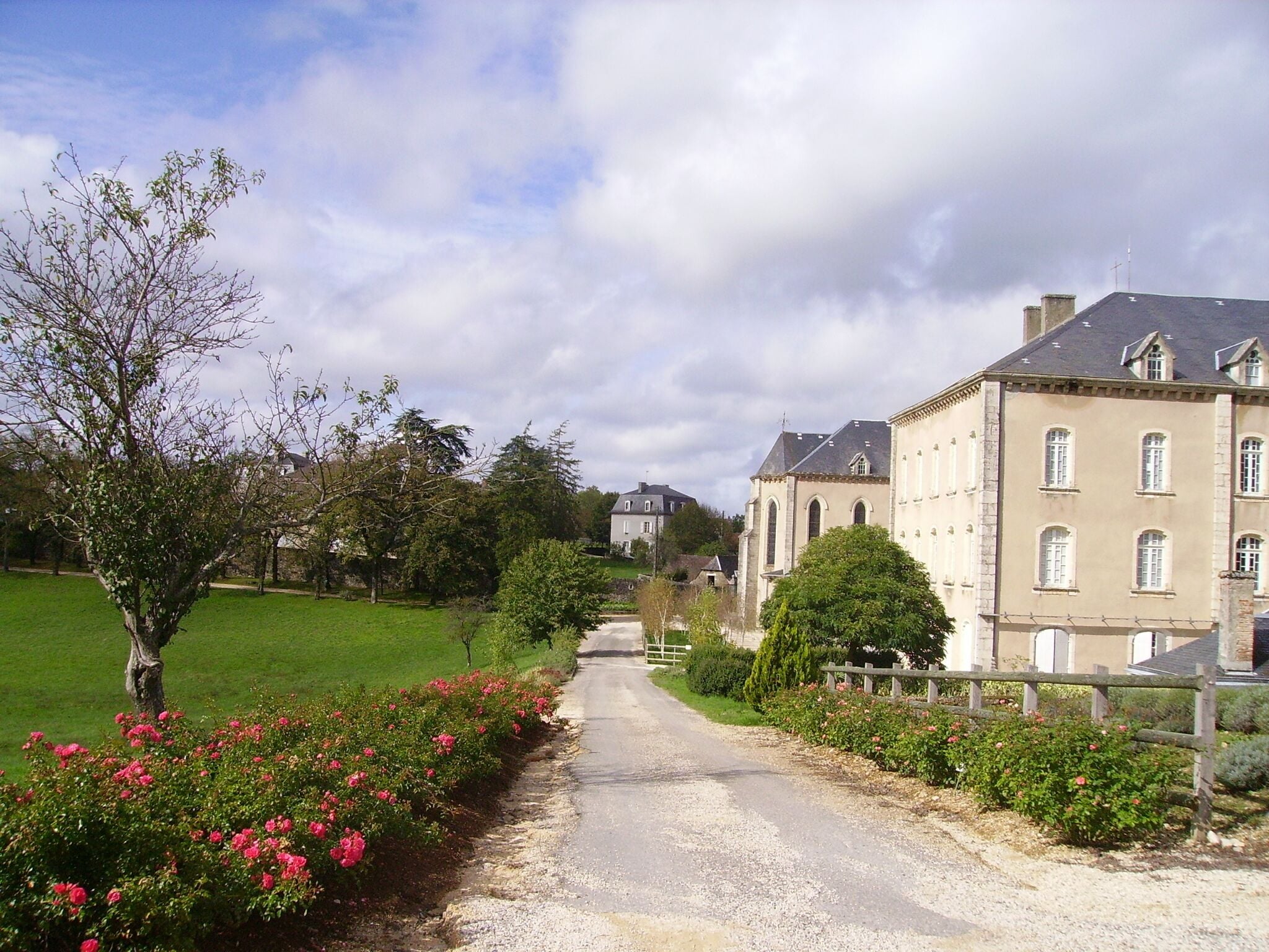 Un chemin pavé mène à un grand bâtiment doté de nombreuses fenêtres et présentant un style architectural traditionnel.