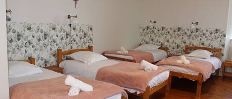 A room with four wooden beds, each with a pink towel and white linens.