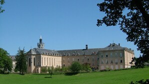 A large, historic building with a prominent tower and multiple windows, surrounded by a well-maintained lawn. - Le Grand Couvent de Gramat (Gramat)